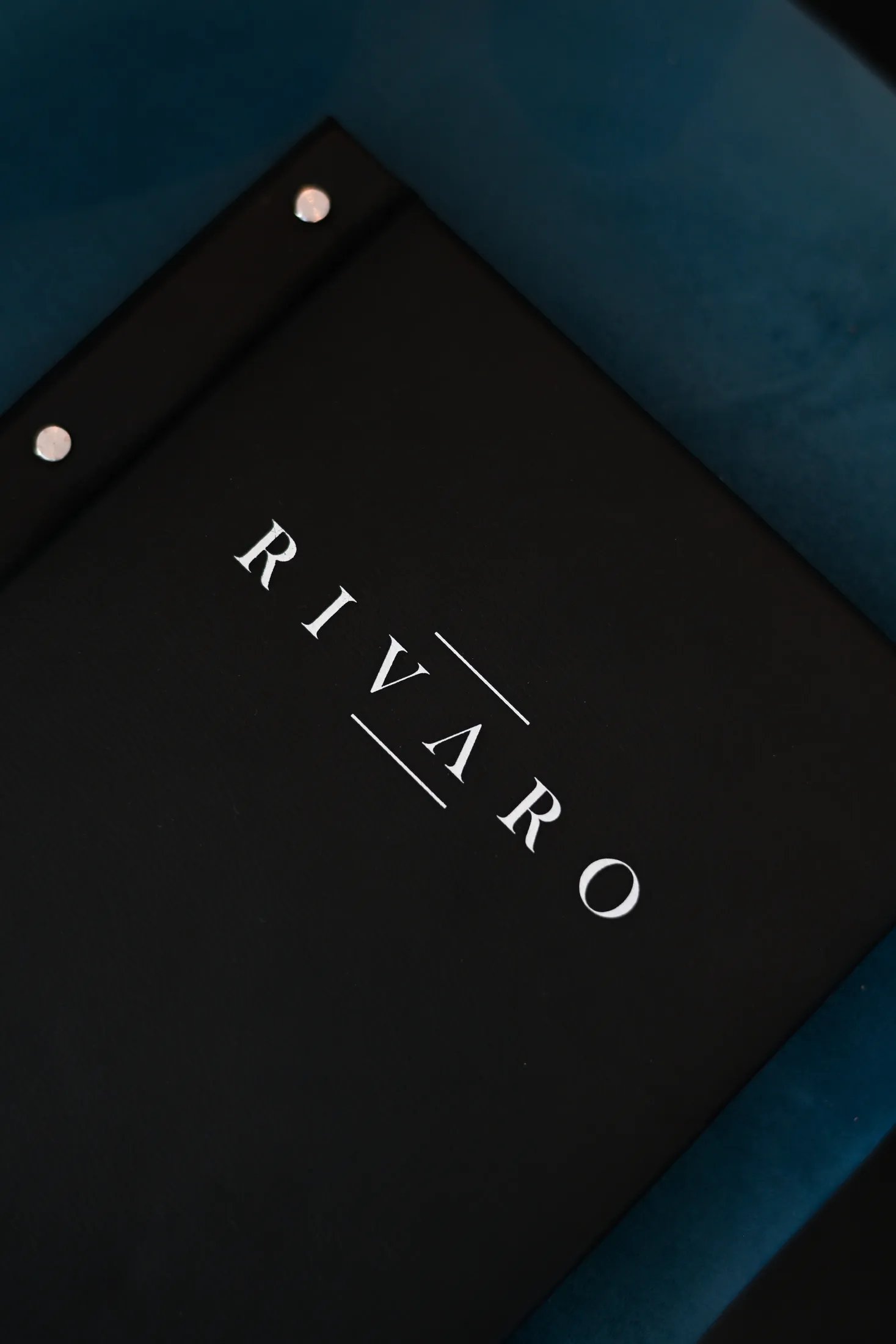 Die schwarze Speisekarte des RIVARO auf blauem Samt